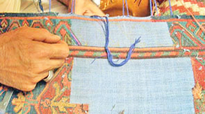 Ein großflächiger Florschaden bei einem Orientteppich wird per Hand repariert Aufwendige Florreparatur ein einem alten Orientteppich